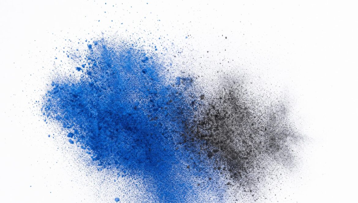Fine blue and black powder particles scattering in the air like a dispersing cloud against a plain white background frozen midmotion in bright studio light | edCircuit Fine blue and black powder particles scattering in the air like a dispersing cloud against a plain white background frozen mid motion in bright studio light