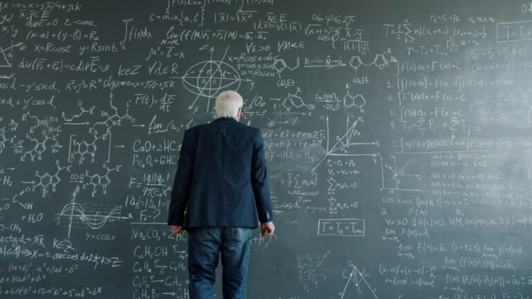 Elderly man looking at complex equations on blackboard