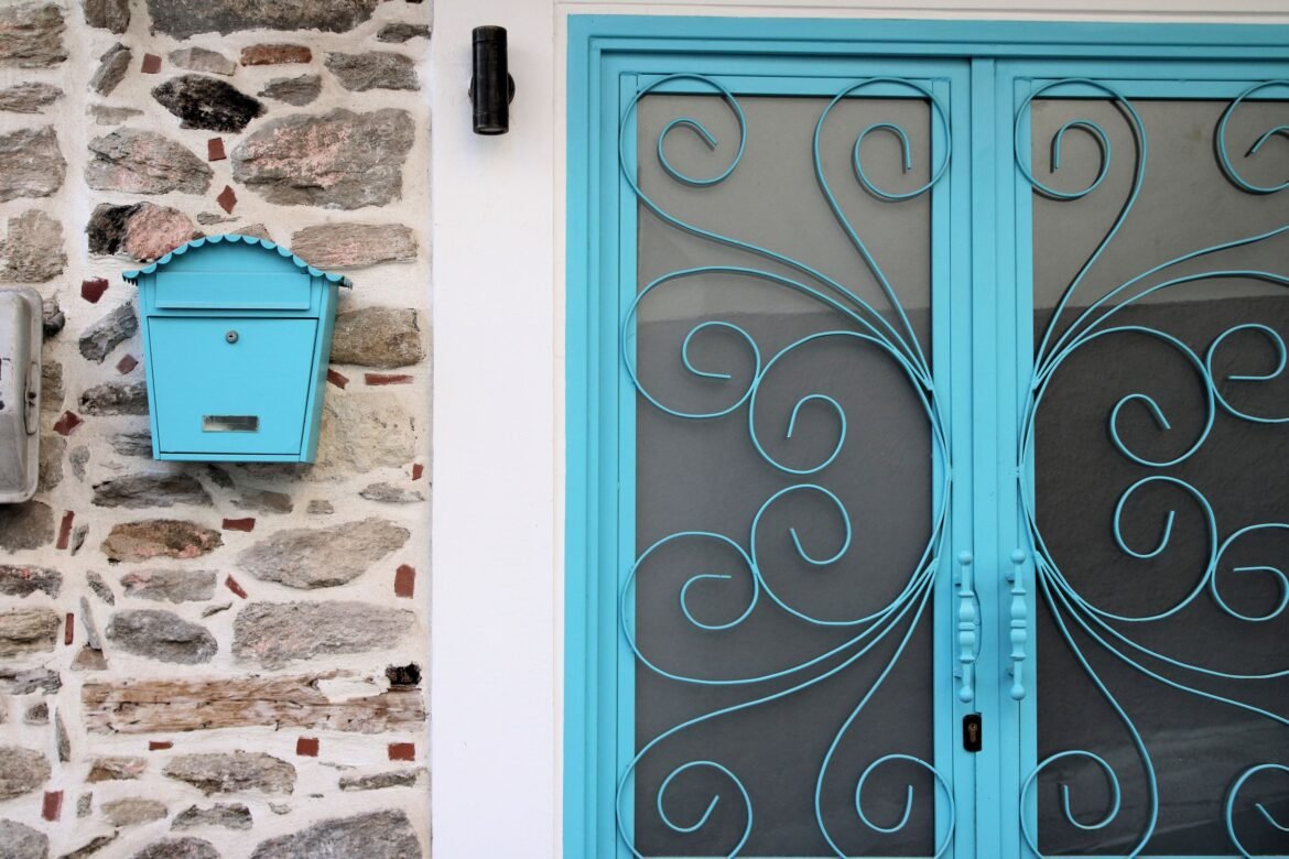 Elegant blue door and vintage mailbox on a stone wall in Kavala, Greec