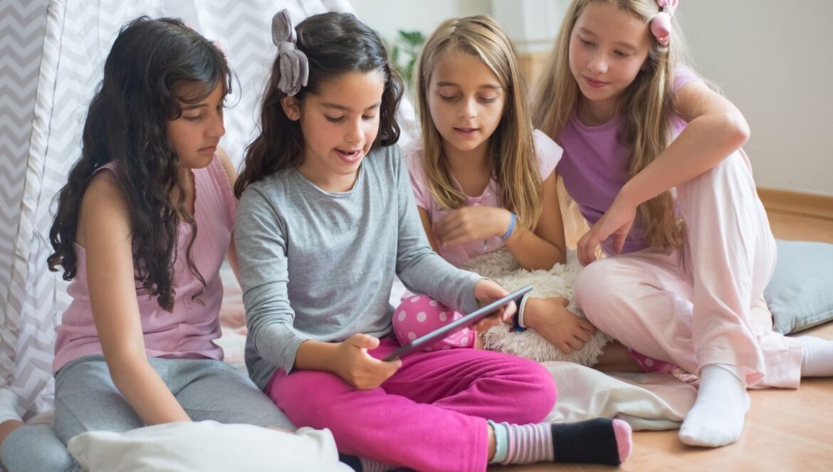 Group of young girls sitting on floor together using tablet inside co | edCircuit Group of young girls sitting on floor together using tablet inside co