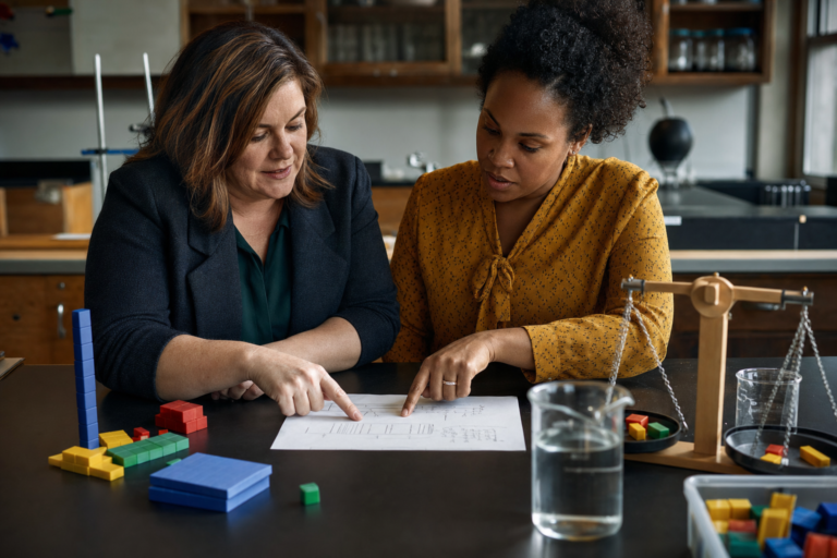 Instructional coach and teacher planning a math and science lesson at a lab bench