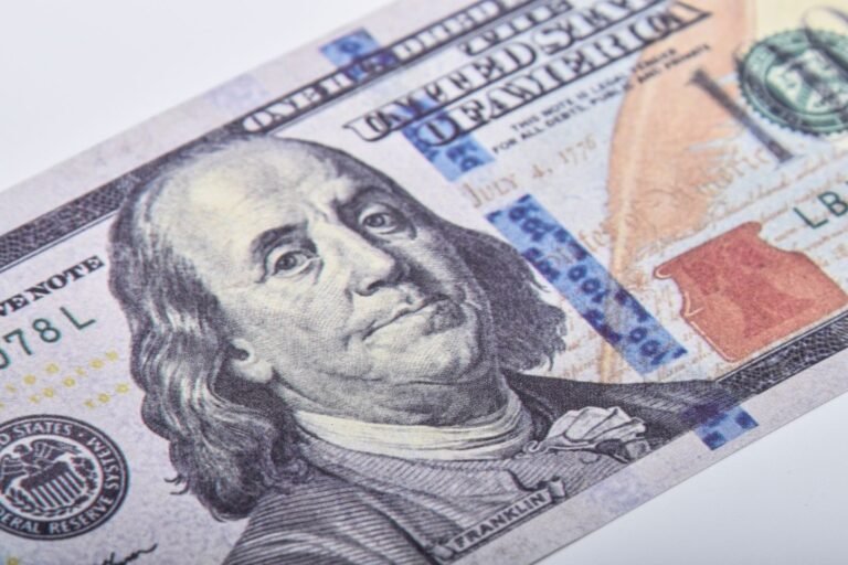 Macro shot of a US hundred dollar bill featuring Benjamin Franklin on a white surface