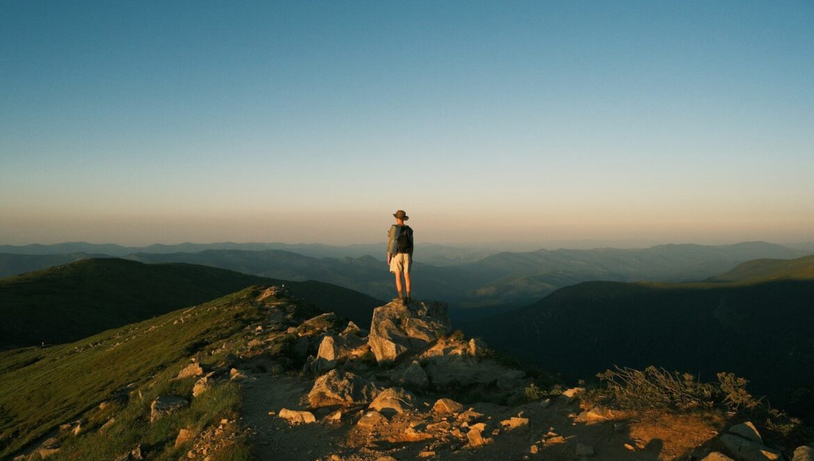 Person standing on a rocky mountain peak at sunset