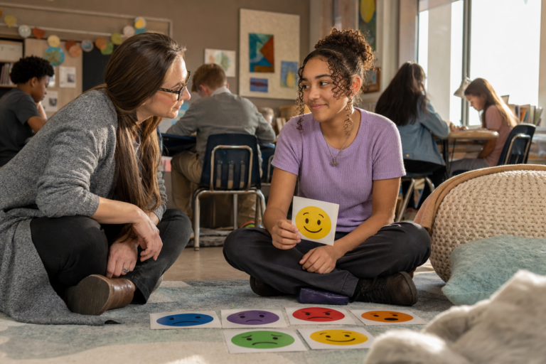 Teacher and student choosing emotion face cards in a calm classroom corner, SEL as prevention and intervention
