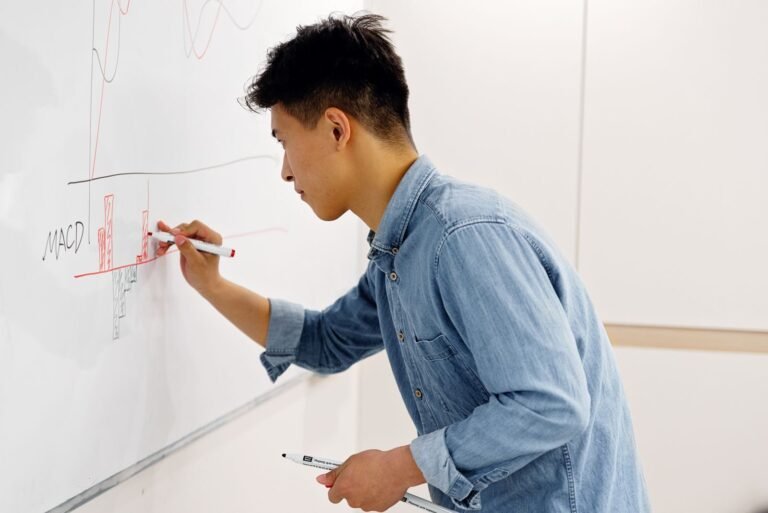 Side view of an adult man writing on a whiteboard focusing on technical analysis and charting
