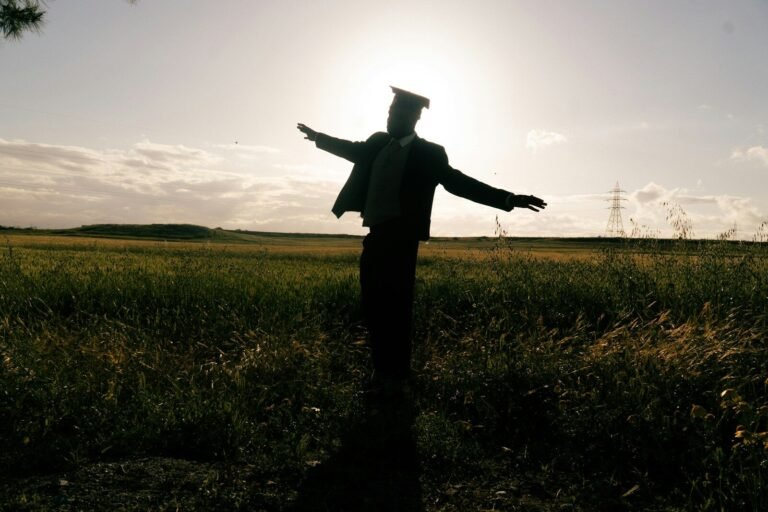 Silhouette of a graduate in a field at sunset