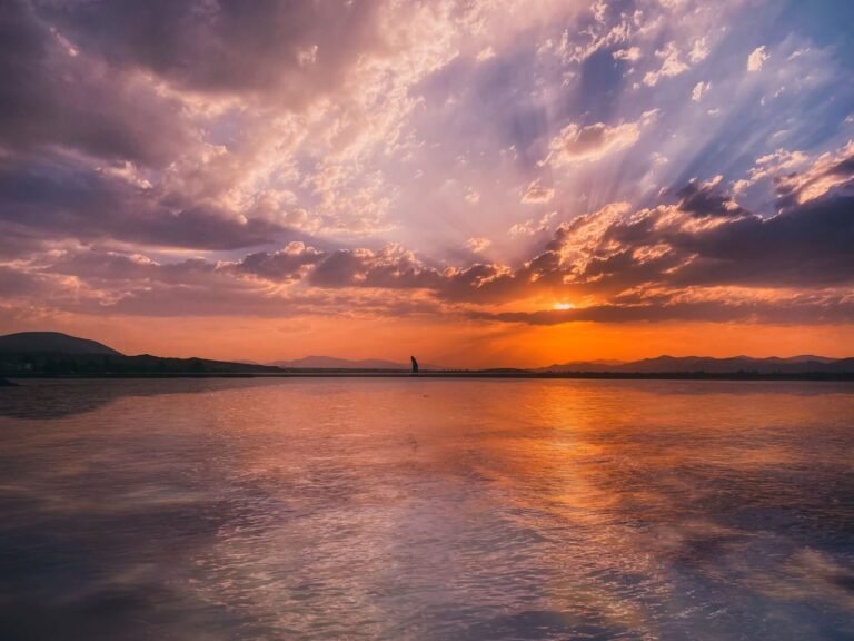 Stunning sunset over a tranquil lake in Armenia with vibrant reflections and a dramatic sk