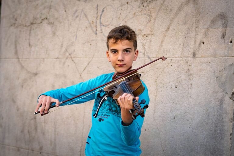 Teenage boy skillfully playing the violin outdoors against a textured wall