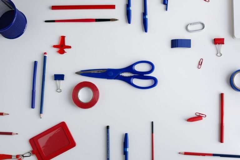 Top view of red and blue office stationery arranged on a white desk, ideal for creative projects