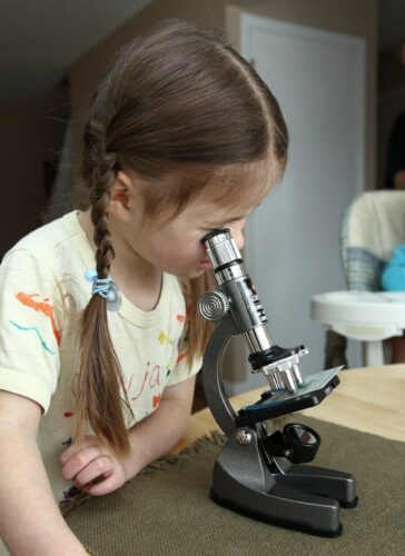 Photo by Anna Khromova | edCircuit A young girl looks intently into a microscope