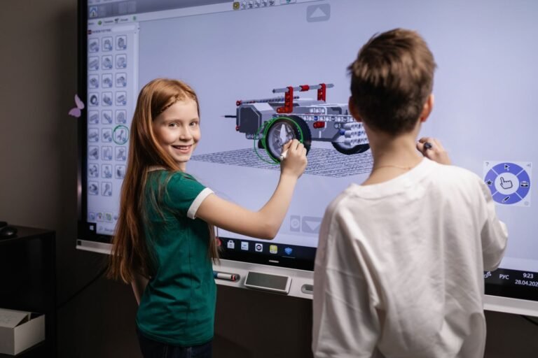 Two children interacting with a digital screen in a classroom setting, learning
