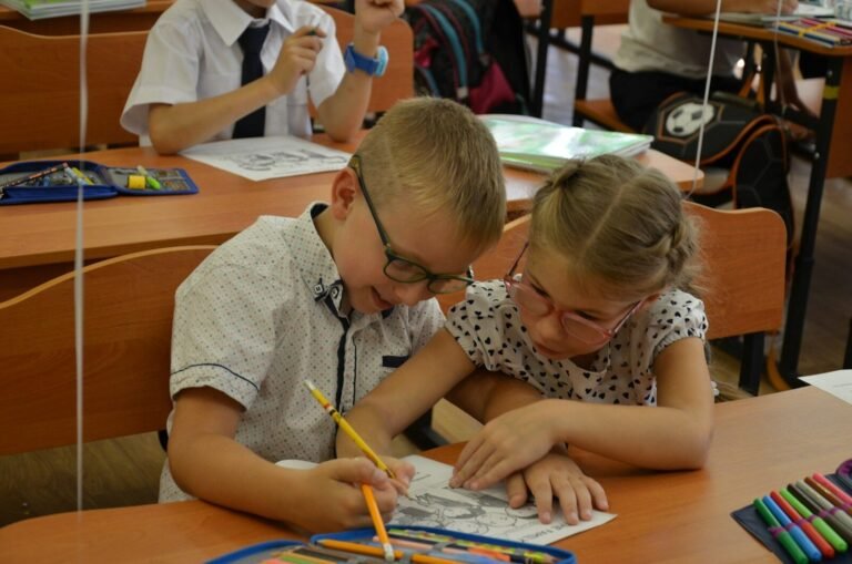 Two young students drawing together in a classroom