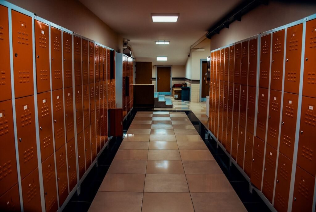 Vacant locker room with orange lockers and tiled flooring in a modern sports facility | edCircuit Vacant locker room with orange lockers and tiled flooring in a modern sports facility