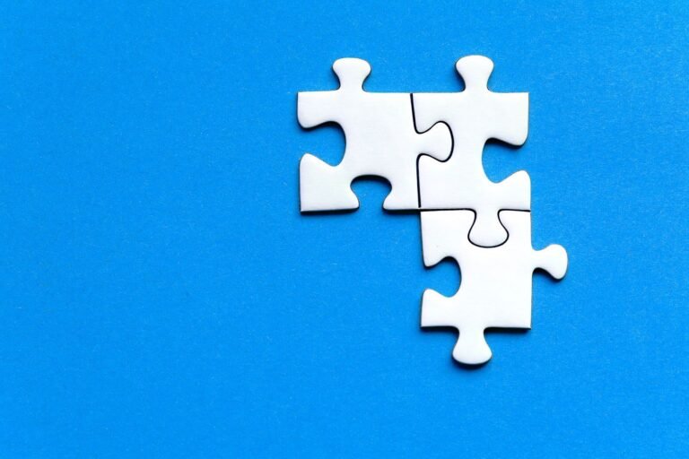 White jigsaw puzzle pieces on a vivid blue background from a top view, perfect for creativ