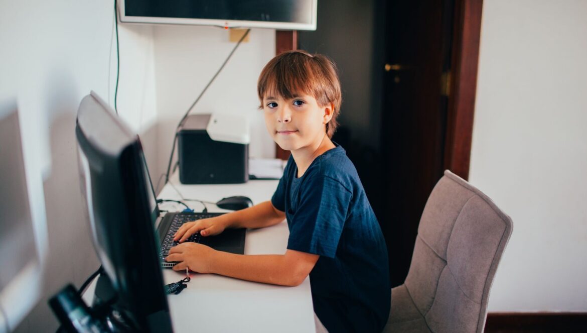 Young boy sitting at a desk using a computer in a home office setting | edCircuit Young boy sitting at a desk using a computer in a home office setting