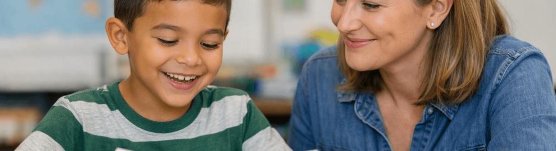 A young boy in a striped shirt reads a book at a desk while a smiling woman sits beside him, encouraging him with methods from the science of reading. The background is a classroom with blurred maps and a whiteboard.
