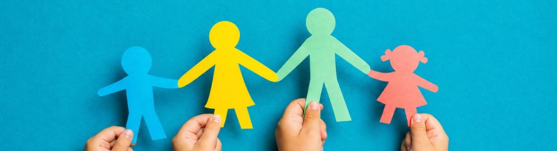 Children's hands holding up colorful paper cut-out figures of a family against a bright blue wall